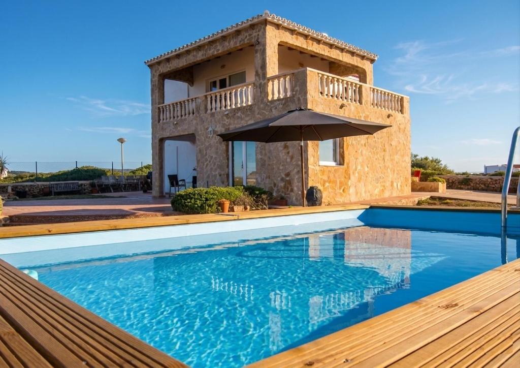 a villa with a swimming pool in front of a house at Villa Miramar Vistas espectaculares in Es Mercadal