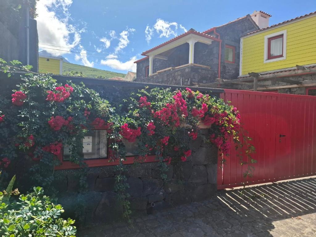 a red fence with flowers on it next to a house at Casas do Lourenço in São Roque do Pico