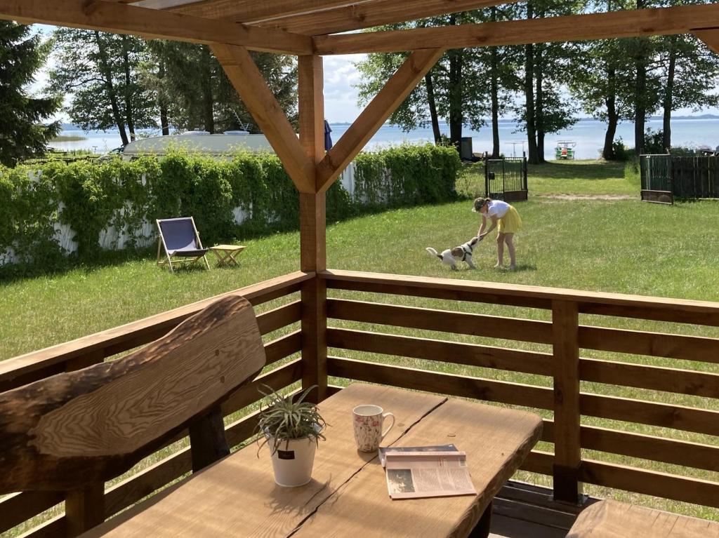 a woman with a dog on a deck with a table at Domki na Mazurach "Malinka" in Suchy Róg