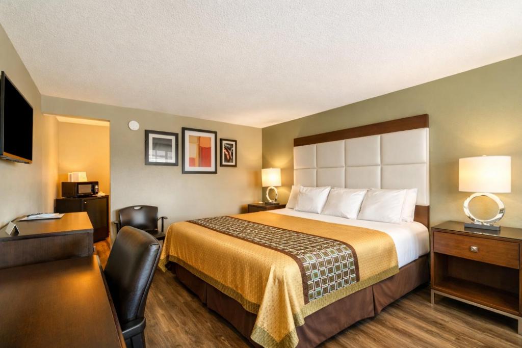 a hotel room with a bed and a desk at Deluxe Inn & Suites By OYO Miami OK in Miami