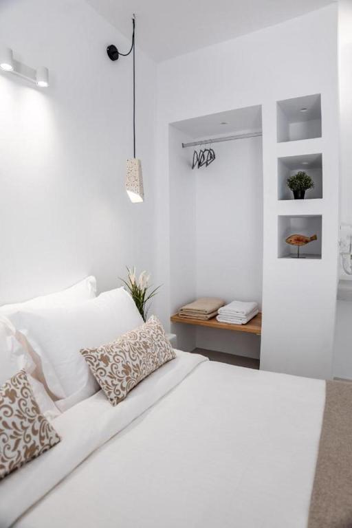 a white bedroom with a white bed with pillows at Mylos Design Suites in Perissa