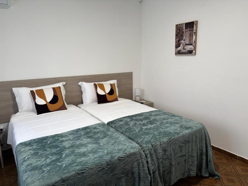 a bedroom with a large bed with a green blanket at Alojamento Local Santo António in Montemor-o-Velho