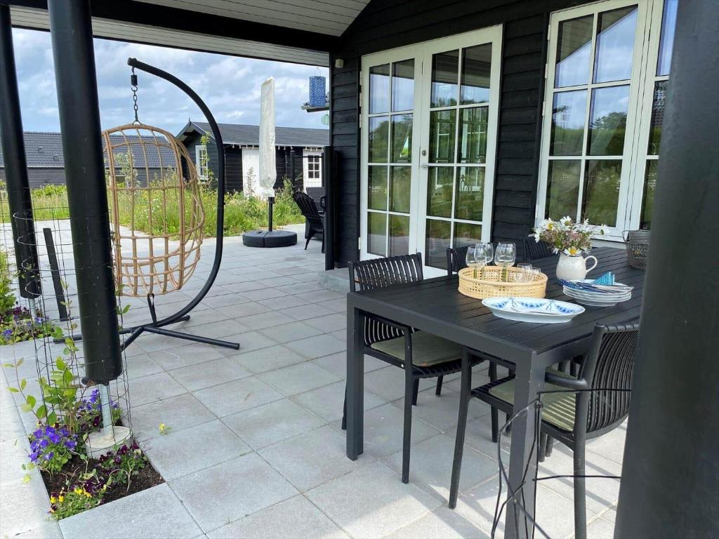 a patio with a black table and chairs and a swing at 17716-Horve-Strandlunden-60 in Hørve