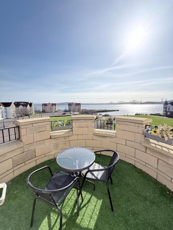 a patio with two chairs and a table on the grass at Penthouse at the Bay near Edinburgh in Saint Davids