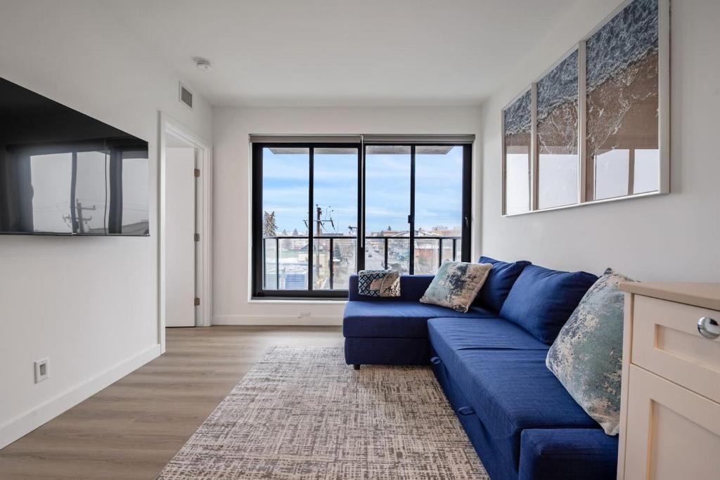 a living room with a blue couch and a large window at Exquisite 2 Bed Condo near DT Core WFree Parking in Calgary