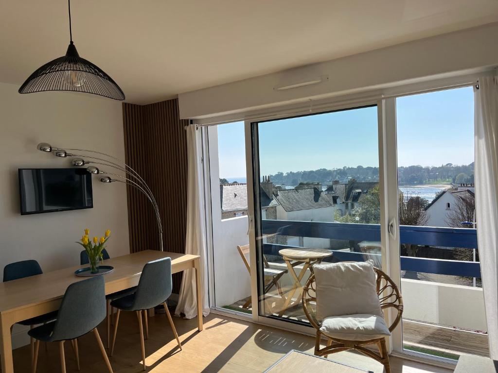 a living room with a table and chairs and a balcony at Appartement vue mer in Bénodet