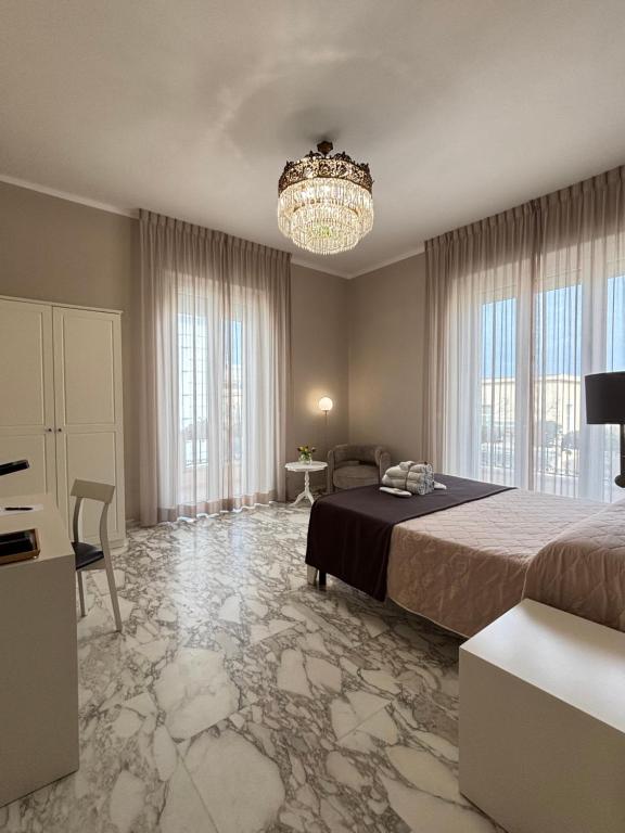 a large bedroom with a bed and a chandelier at Faro Bianco Gallipoli - Suites & Apartments in Gallipoli