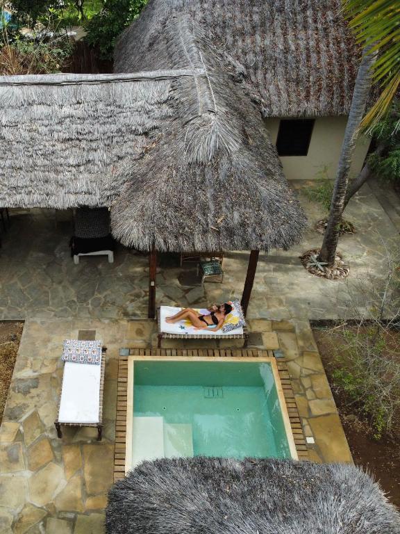 an overhead view of a swimming pool with a straw umbrella at 1, 2 bed bungalow Watamu in Watamu