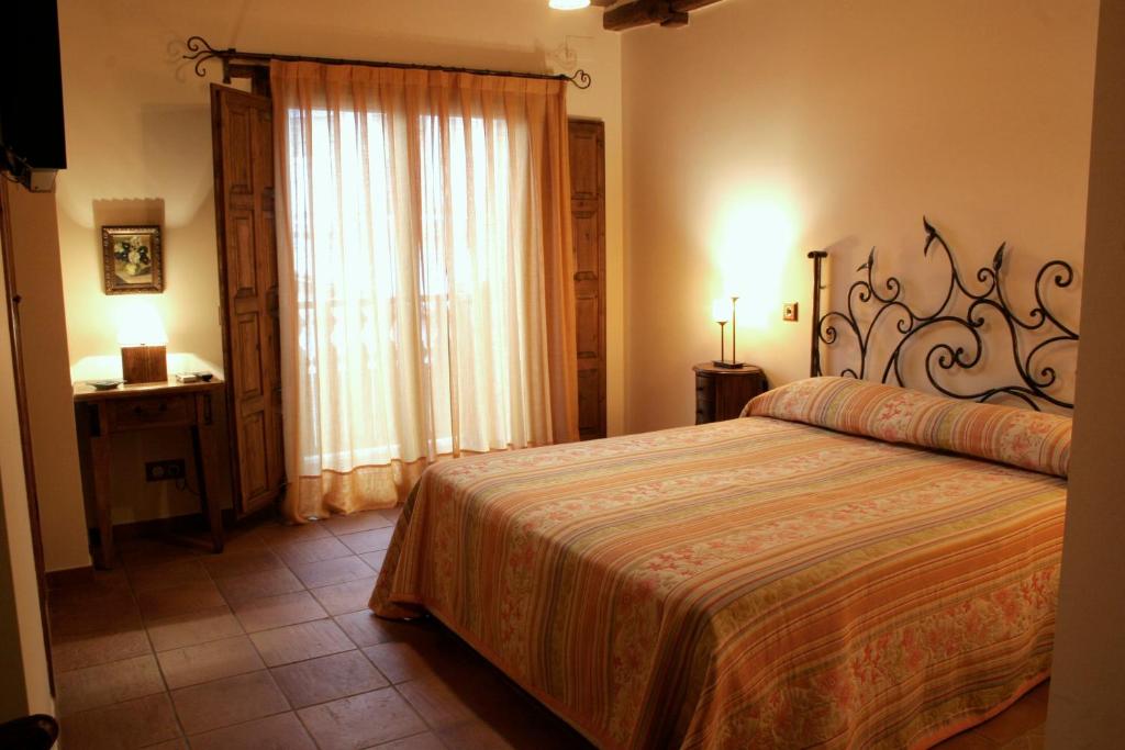 Un dormitorio con una cama grande y una ventana. en Posada La Gatera, en Pedro Bernardo