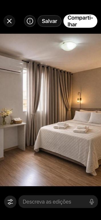 a bedroom with a white bed and a window at Aconchego in Maringá