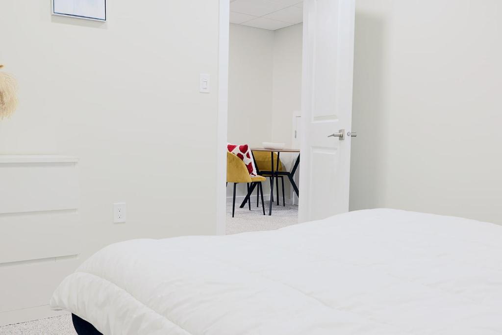 a white bedroom with a bed and a table at Bright Modern Suite in Bonavista, Private Entrance with Free Parking in Winnipeg