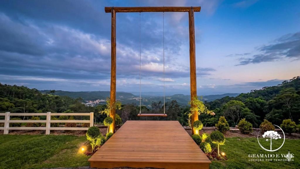 a wooden boardwalk with a view of the mountains at Refúgio em Gramado | cabana c/ hidromassagem in Gramado