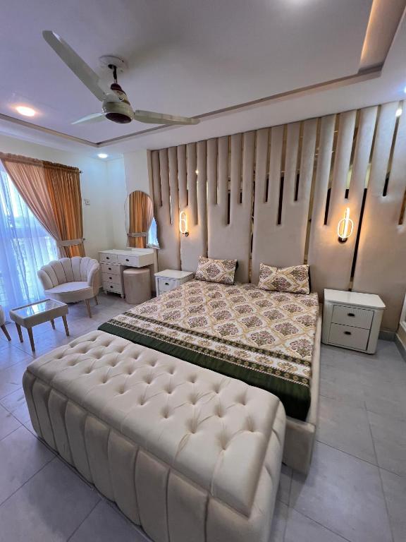 a bedroom with a large bed with a large tufted couch at apartment for rent in Islamabad