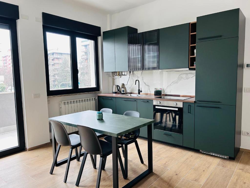 a kitchen with green cabinets and a table and chairs at NUVOLA Hosting in Segrate