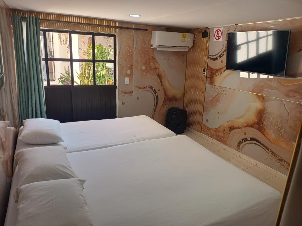 a room with three beds and a tv and a window at Hostal Doña Betty 2 in Cartagena de Indias