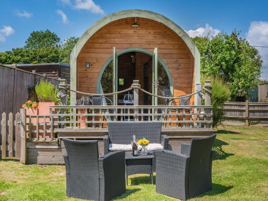 a wooden building with a table and chairs in a yard at The Pod At Egmont in Newenden