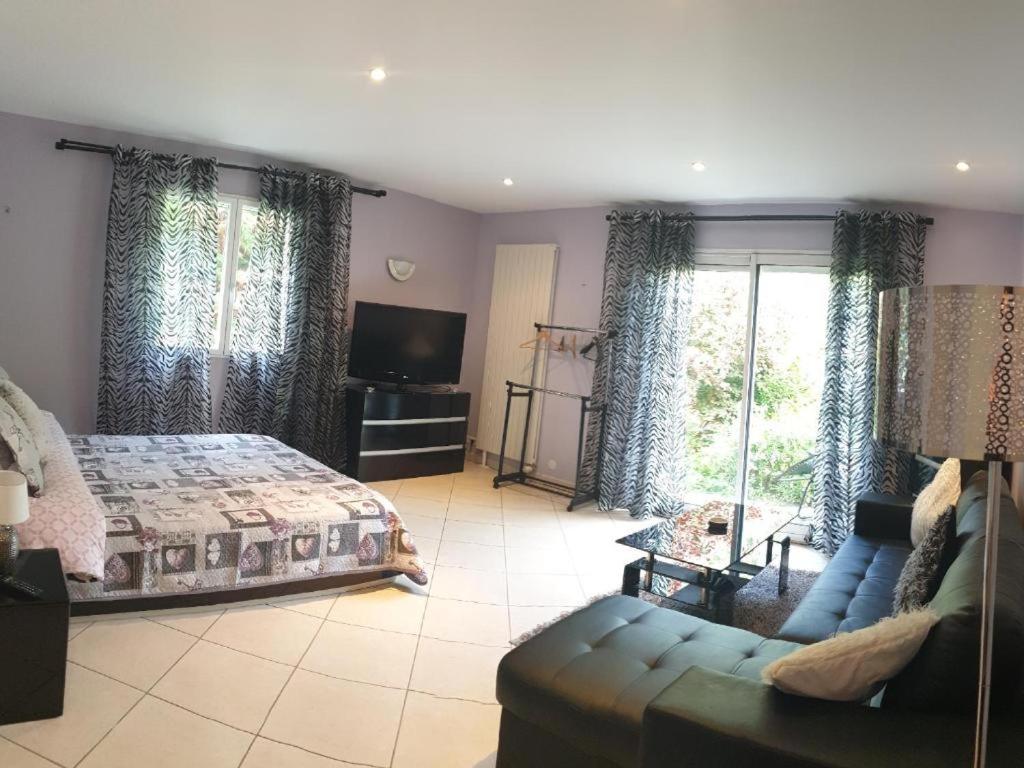 a bedroom with a bed and a couch and a tv at STUDIO Confort Clim 20min Orly-45min Paris Disney in Corbeil-Essonnes