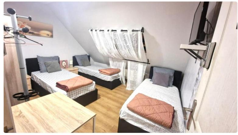 a small room with three beds and a television at La Julia Chambre meublée près de Paris in Corbeil-Essonnes