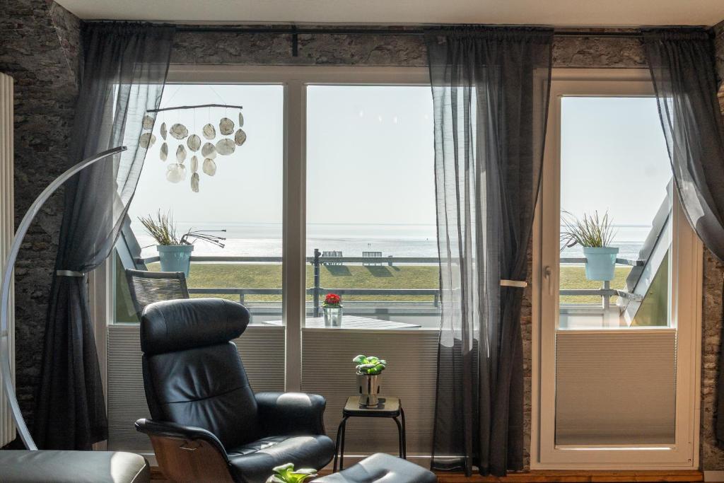 a living room with a chair in front of a window at Encore Seaside in Büsum