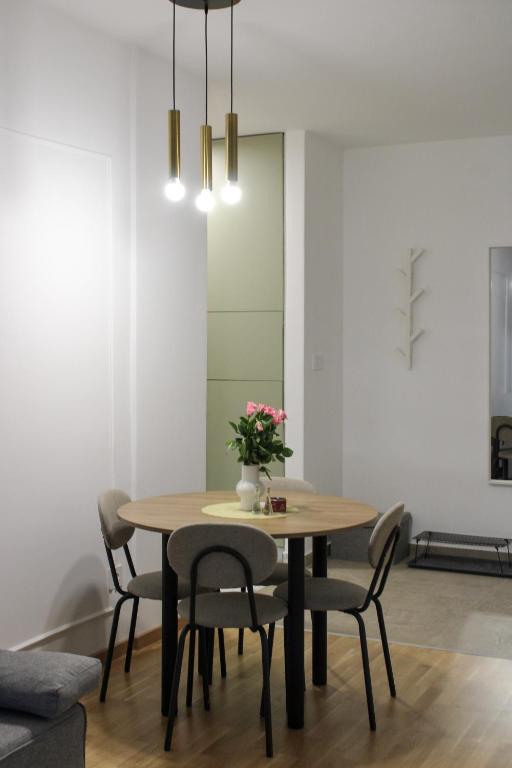 a dining room table with chairs and a vase of flowers at Square Garden apartment in Novi Sad