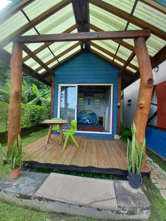 a shed with a wooden deck with a table and a green chair at Fare Te Ava Iti in Teahupoo