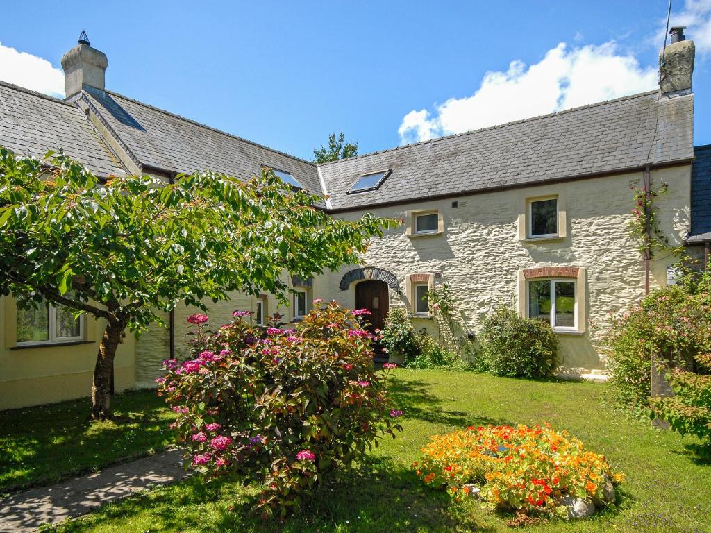 an old stone house with flowers in the yard at Yr Hen Felin in Mathry