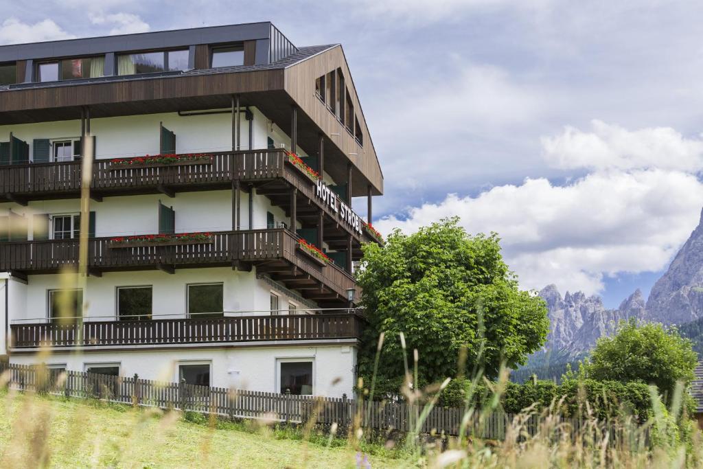 a building with balconies and trees in front of mountains at Hotel Strobl in Sesto