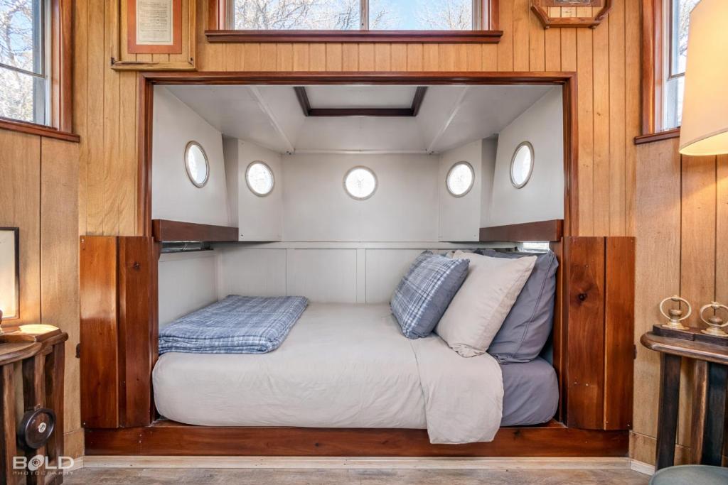 a bed in the middle of a room with windows at Shipwreck with upper deck, Dock Access, Kayaks in Karnack