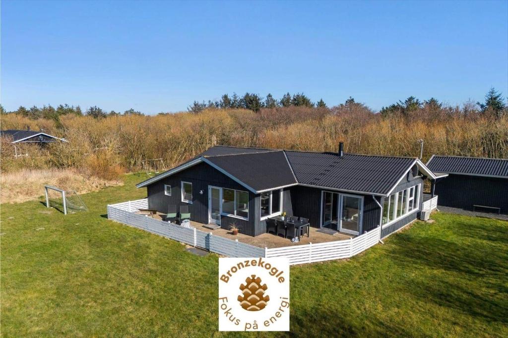 a house with a black roof on a grass field at 1102-Ringkobing-Gransangervej-14 in Nørby