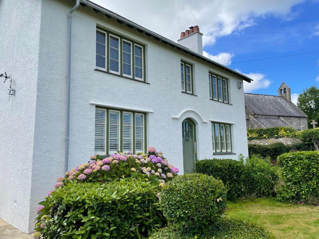 a white house with flowers in front of it at Ty Mawr Farm in Llanfairpwllgwyngyll