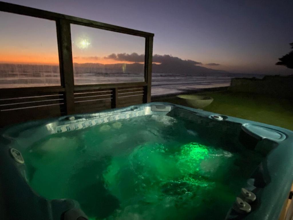 a jacuzzi tub with a view of the ocean at Raumati Sunsets in Raumati Beach
