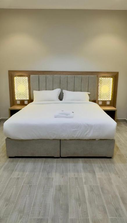 Ein Schlafzimmer mit einem großen weißen Bett und Holzboden in der Unterkunft Alturya in Al-'Ula