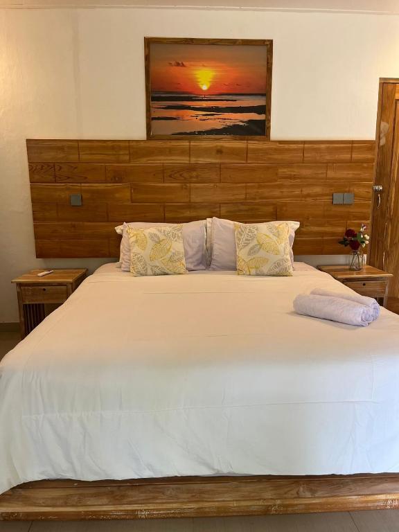 a bedroom with a large white bed with a wooden headboard at Sunset Rote Bungalows in Nembrala