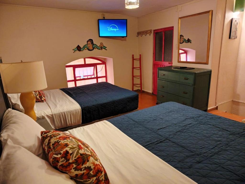 a bedroom with two beds and a tv on the wall at Rinconcito de Galarza 28 in Guanajuato