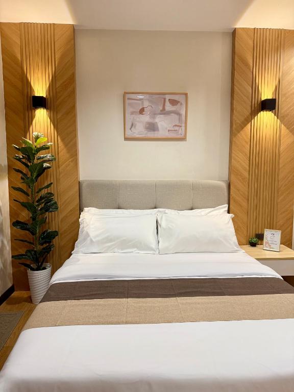 a bedroom with a large white bed and a plant at Lafontana Hometel in Roxas City