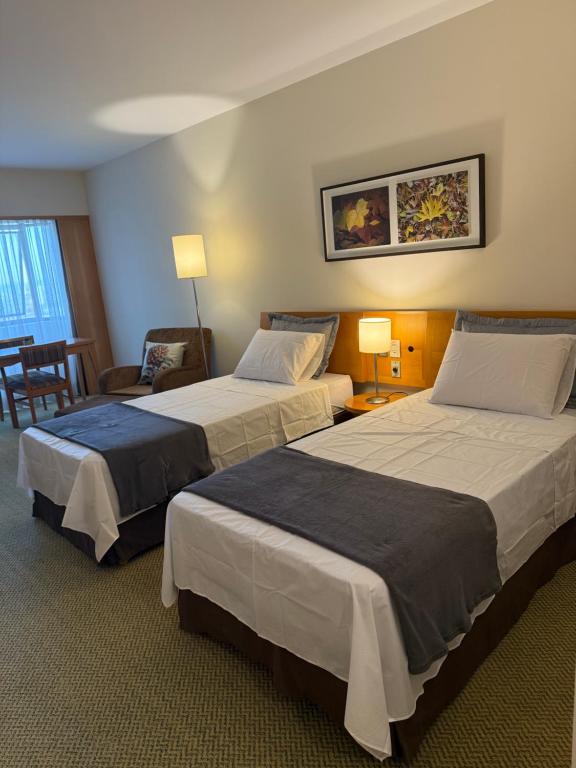 a hotel room with two beds and a chair at Sol Alphaville Hotel & Residence 1004 in Barueri