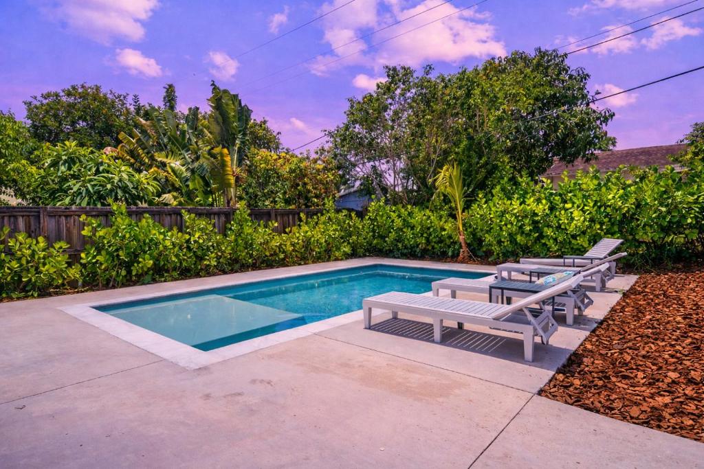 a swimming pool with two benches and a table at Private Pool w Guest House Northwood Hills in Riviera Beach