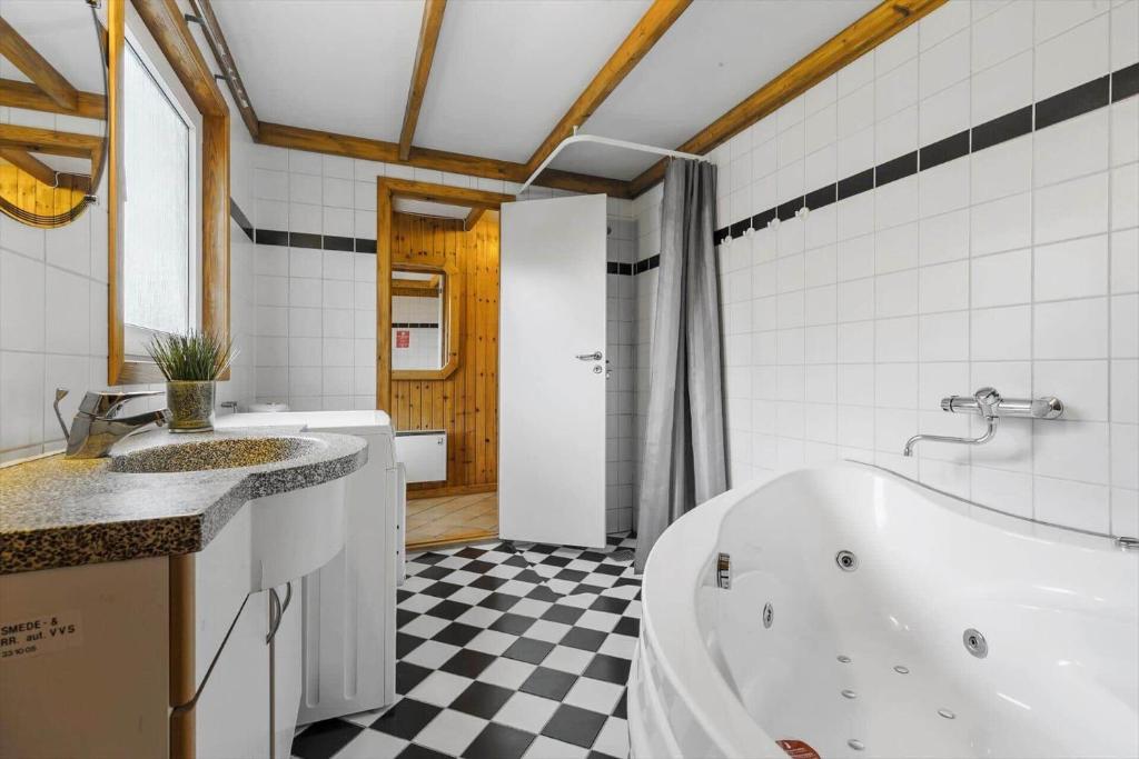 a bathroom with a white tub and a black and white checkered floor at 8116-Ega-Under-Ronnene-37 in Egå
