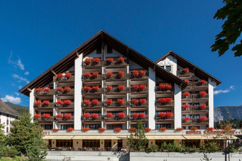 a hotel with red flowers on the balconies at Hotel Laaxerhof in Laax