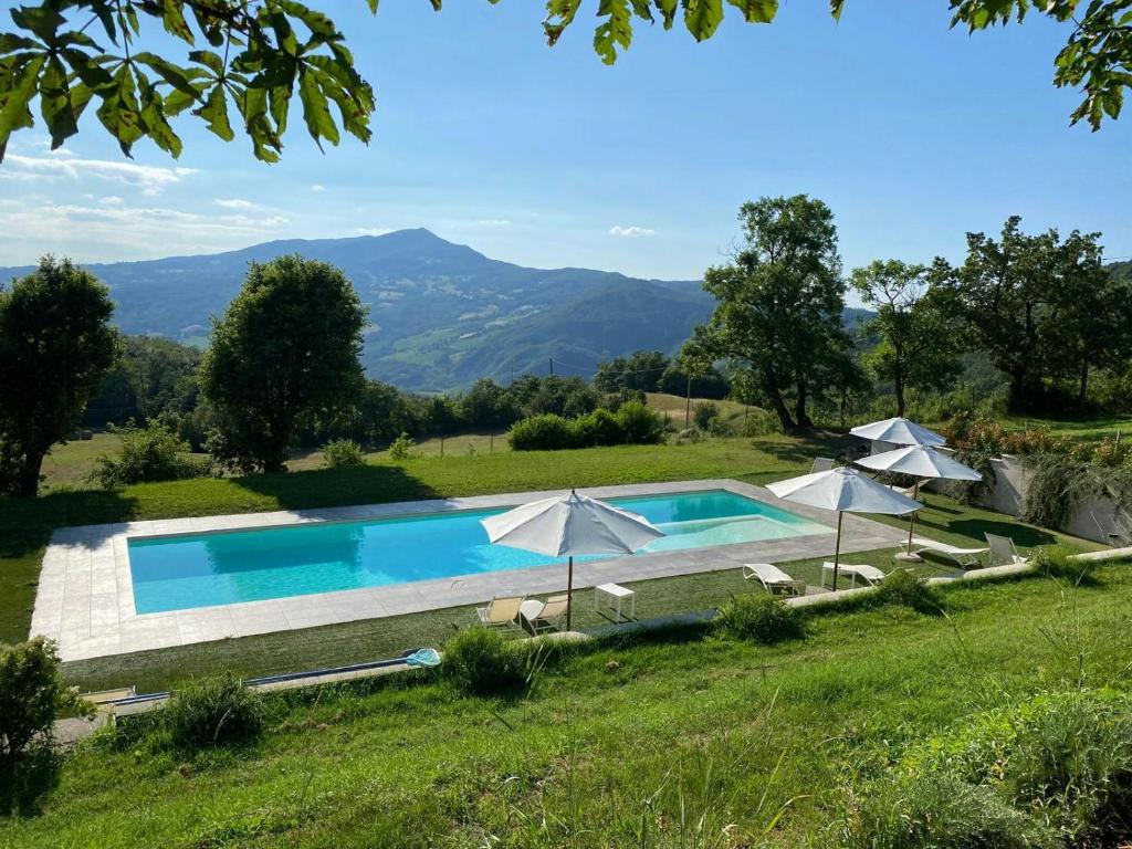 a swimming pool in a field with umbrellas at Mountain Farmhouse Between Parma And Cinque Terre in Solignano
