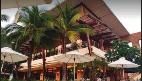 a building with palm trees and umbrellas in front of it at Pico hamilo coast condotel suite in Nasugbu