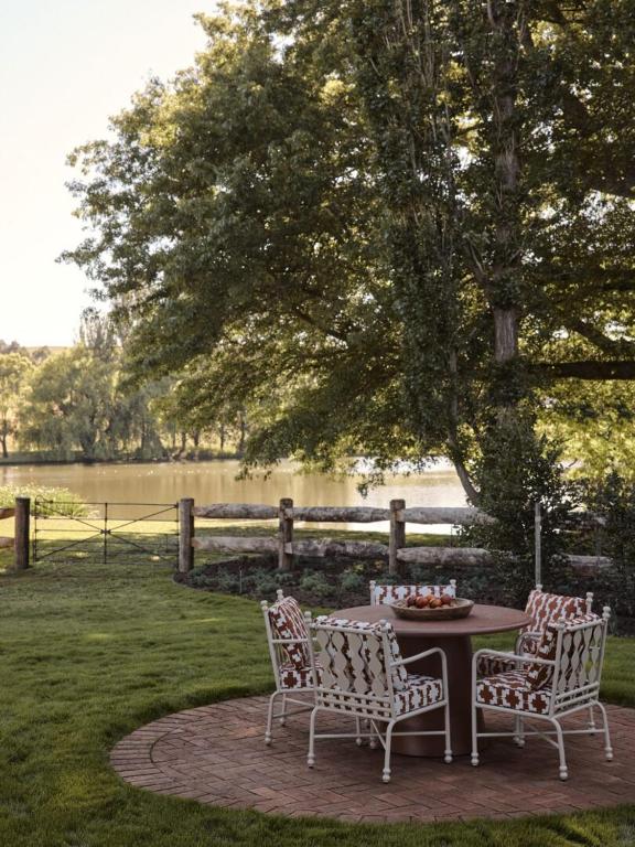 two chairs and a table in a yard with a tree at Bendooley Estate in Berrima