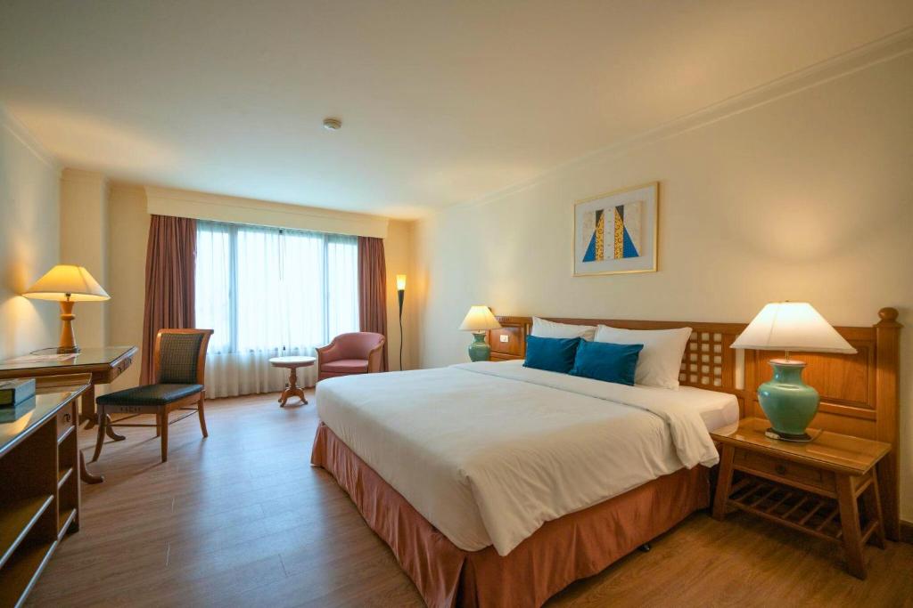 A classic-style double room with a large bed, desk and window-side seating.