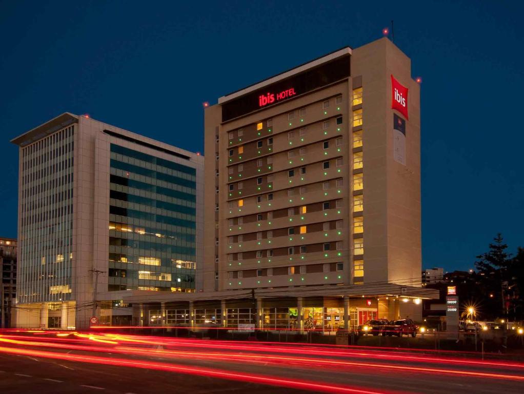 a hotel building with a sign on it at night at ibis Concepcion in Concepción