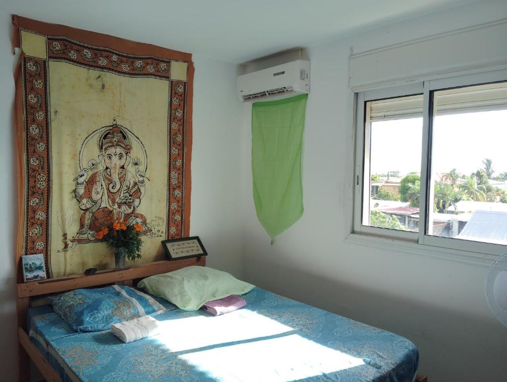 a bed in a room with a painting on the wall at La chambre Ganesh in Saint-André