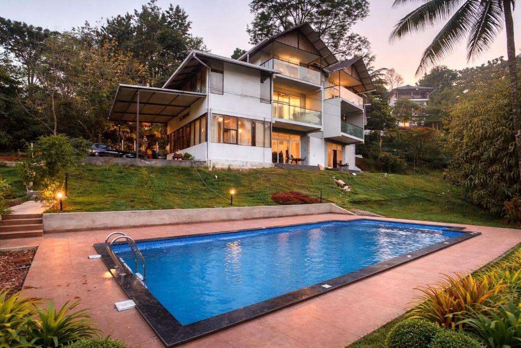 a house with a swimming pool in front of a house at Velvet Revive Munnar in Munnar