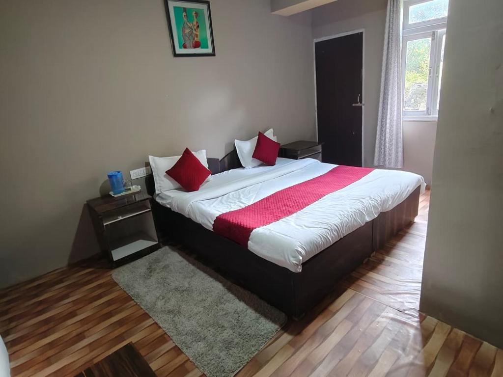 a bedroom with a large bed with red pillows at Hotel Silver Cloud in Pelling
