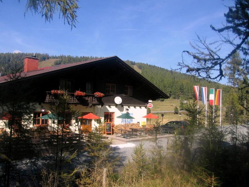 ein Gebäude mit Tischen und Sonnenschirmen davor in der Unterkunft Gasthof Alpl in Sirnitz