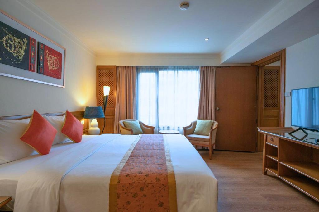 A classic guest room showing a large bed, television, seating by the window, and built-in storage.