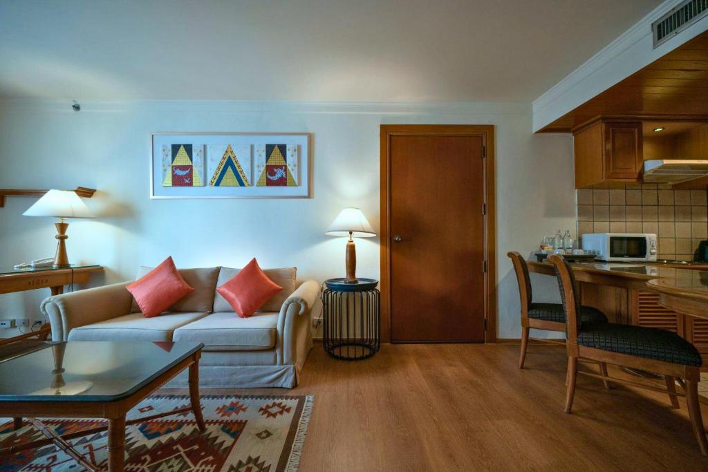 A suite-style living area with a sofa, dining/work table, and compact kitchen.